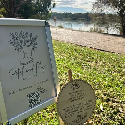 Outdoor signs promoting nature-led learning by a lakeside path on a sunny day.