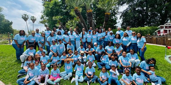 Large group of people wearing matching blue shirts posing outdoors.