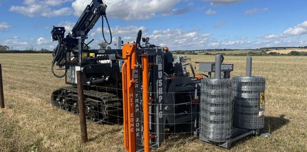 Machine installing fencing posts in a rural field.