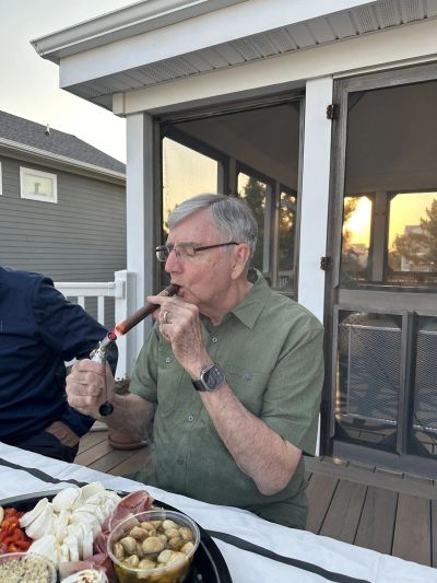 Man lighting a cigar outside at sunset.