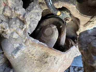 Close-up of a rusted, dusty mechanical part with a wire connection.