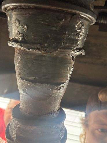 Close-up of a heavily worn and damaged metal component under a vehicle.