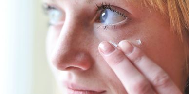 Woman applying cream near her eye