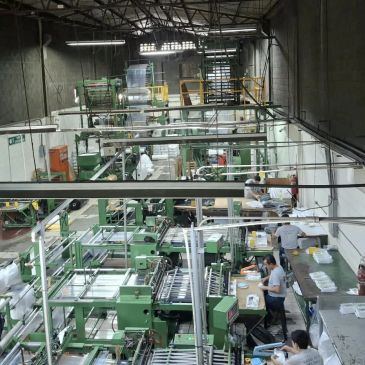 Fábrica con maquinaria verde y trabajadores.