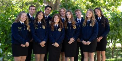 Group of young people in matching blue jackets posing outdoors.
