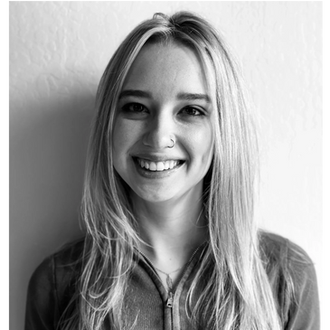 Black and white portrait of a smiling young woman with long hair and a nose ring.