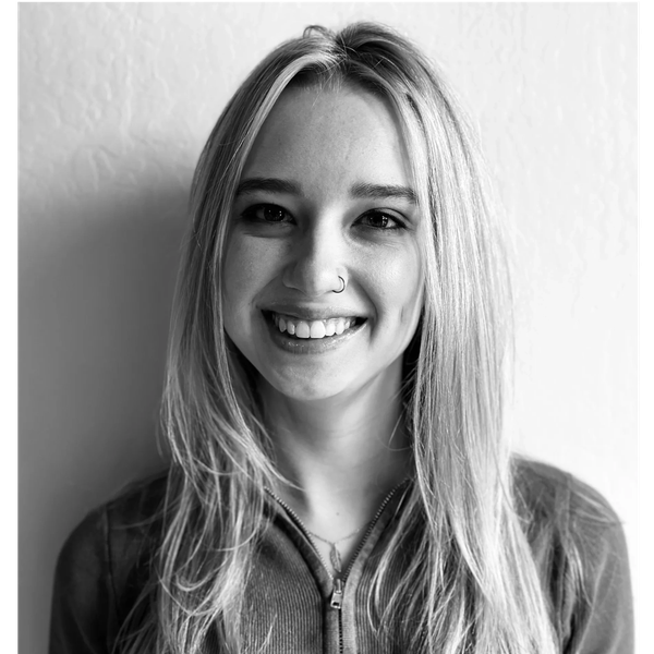 Black and white portrait of a smiling young woman with long hair and a nose ring.