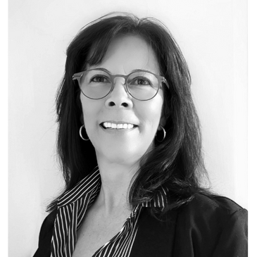Black and white portrait of a smiling woman with glasses and hoop earrings.