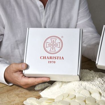 Person holding a Charistia 1970 box with communion wafers and flour on a table.