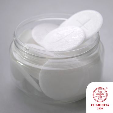 Clear jar filled with white cotton pads, embossed with crosses, on a smooth surface.