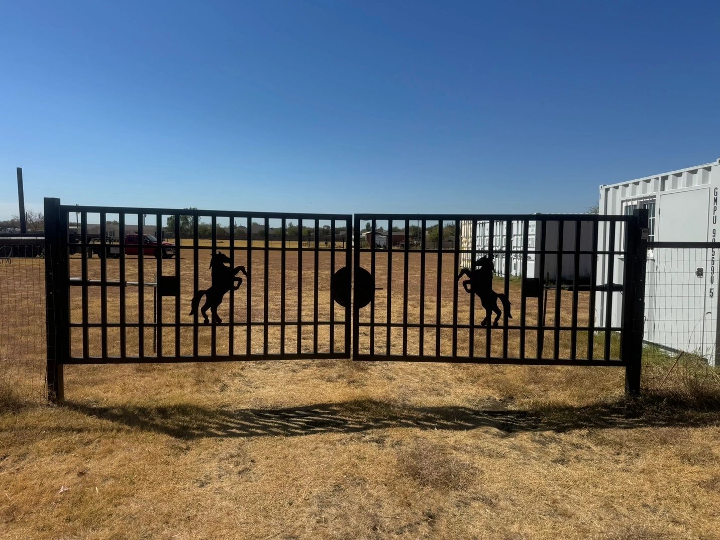 Black entry gate with horse silhouettes at the fenced storage and truck parking yard in Ponder, Texa