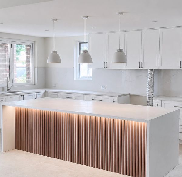 Modern kitchen with illuminated island and pendant lights.