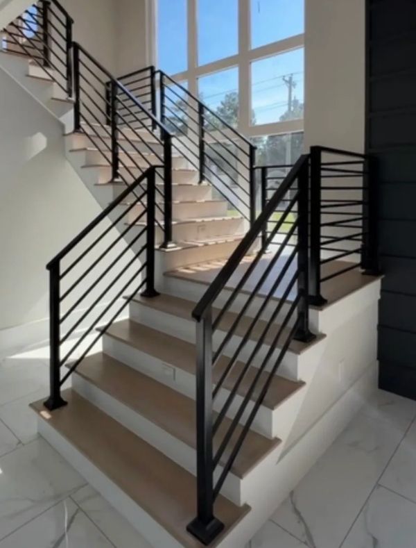 Modern staircase with black metal railings and large windows letting in natural light.