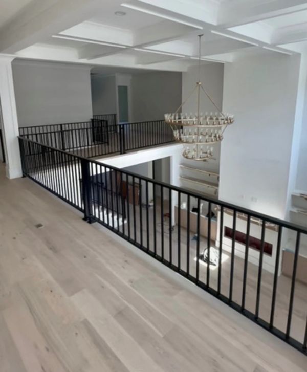 Spacious modern hallway with black railings and wooden flooring.