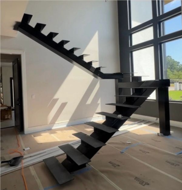 Modern black metal staircase without railings in a bright room.