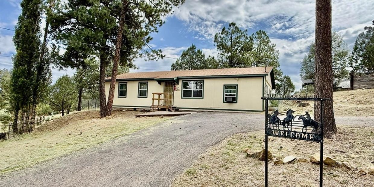 Single-story house with a driveway and welcome sign.