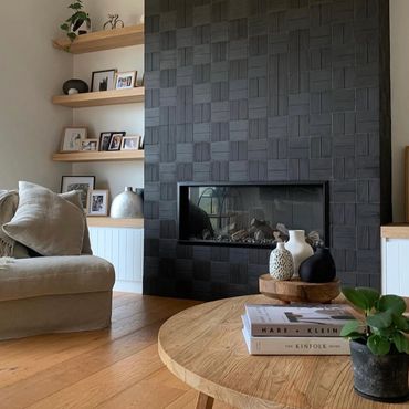 Cozy living room with a textured black fireplace and wooden accents.