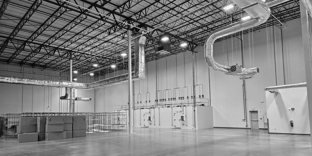 Empty industrial warehouse with high ceilings and ductwork.
