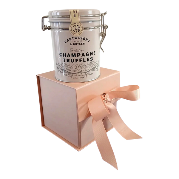 Tin containing champagne truffles sitting on rose gold gift box with matching ribbon