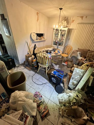 A cluttered and dirty living room with scattered papers and furniture.