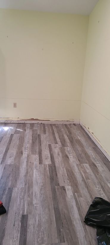 Empty room with new gray wood flooring and pale yellow walls.