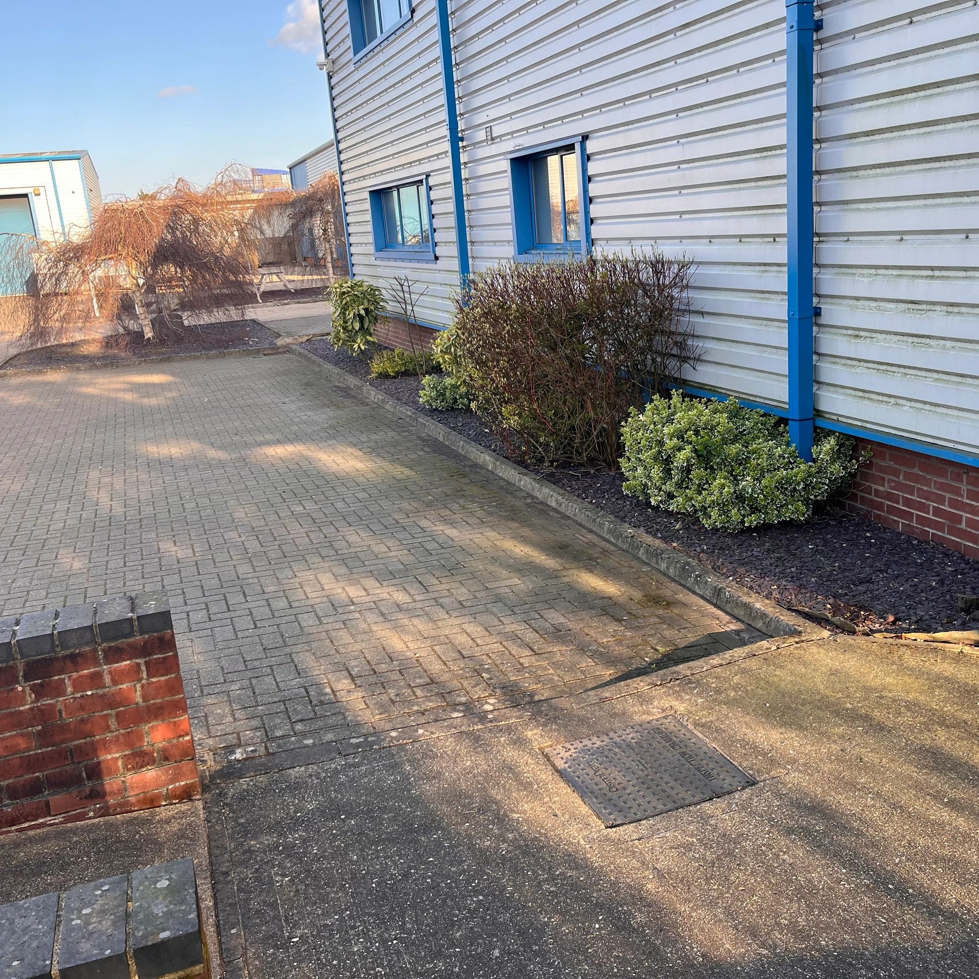 Commercial office car park with blue slate and trimmed shrubs.