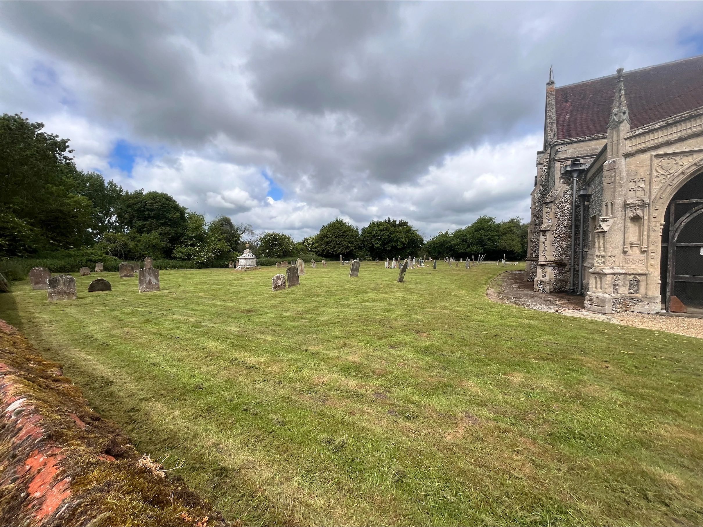 The grounds of a church with the lawn cut and headstones strimmed around.