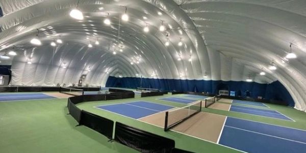 Indoor tennis courts under a large dome structure.