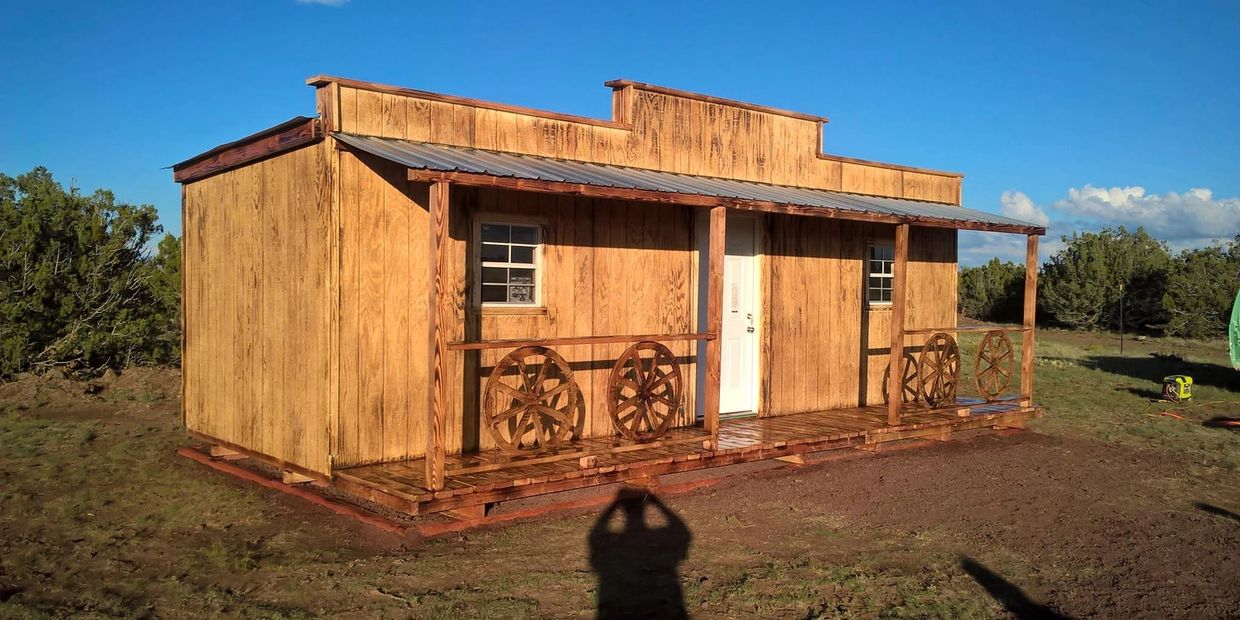 Rustic wooden cabin with wagon wheel railings under clear blue sky.