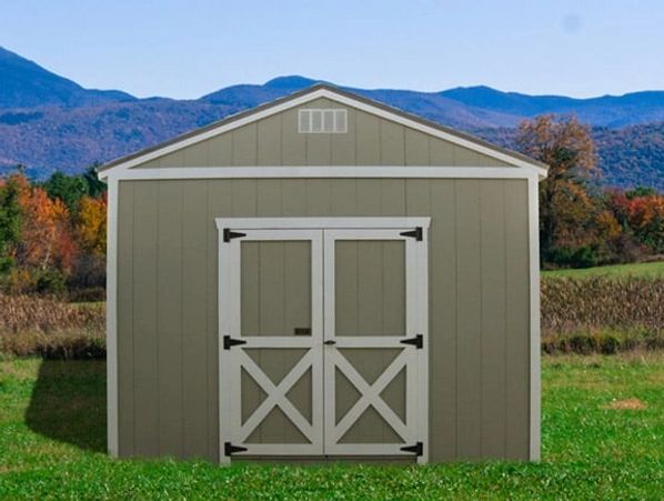 A gray storage shed with white double doors in a grassy field.
