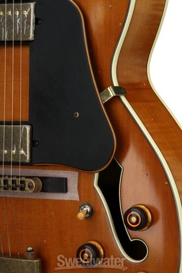 Close-up of a vintage hollow body electric guitar with wood finish and metal pickups.