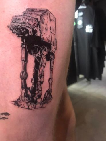 Black ink tattoo of an AT-AT walker from Star Wars on skin.