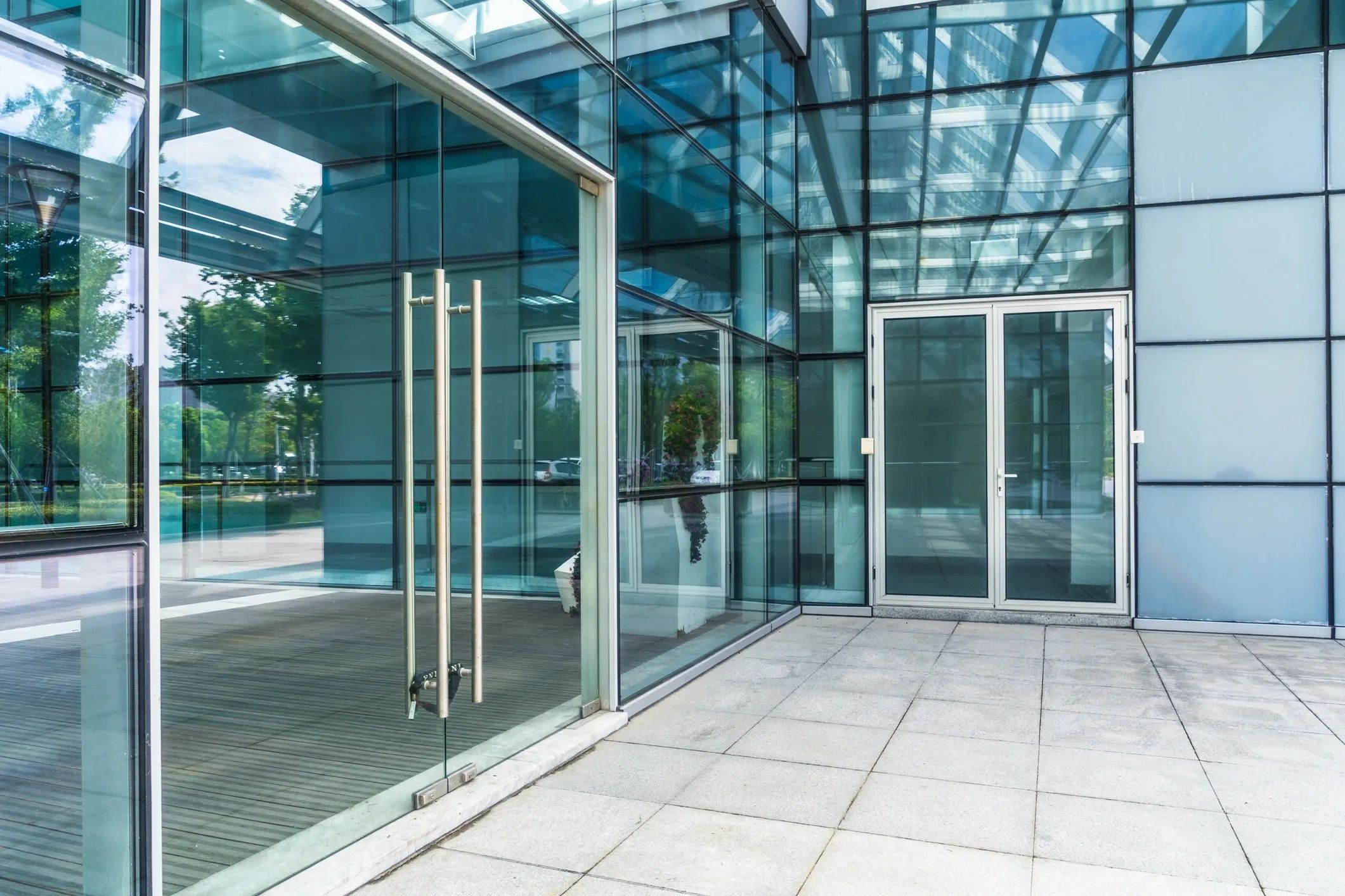 Modern glass building entrance with reflections.