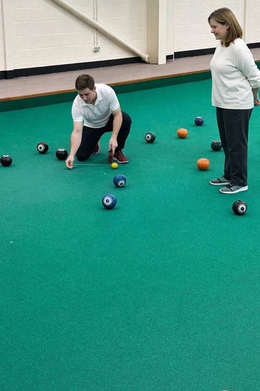 Two players measuring on an indoor bowls green