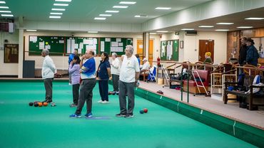 A group of bowls club players standing on an indoor green