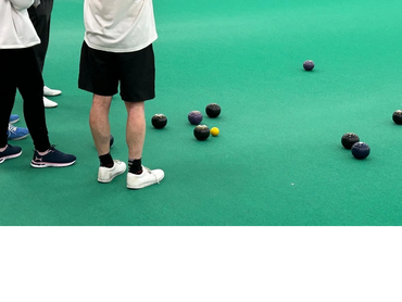 Three figures standing around several bowls and a jack.