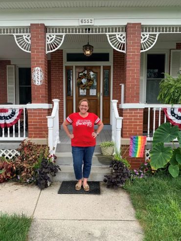 Woman in red shirt on front porch steps
