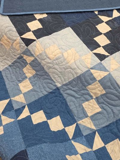 Patchwork quilt with blue and beige tones.