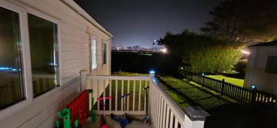 Nighttime view of a porch with children's toys and a backyard.