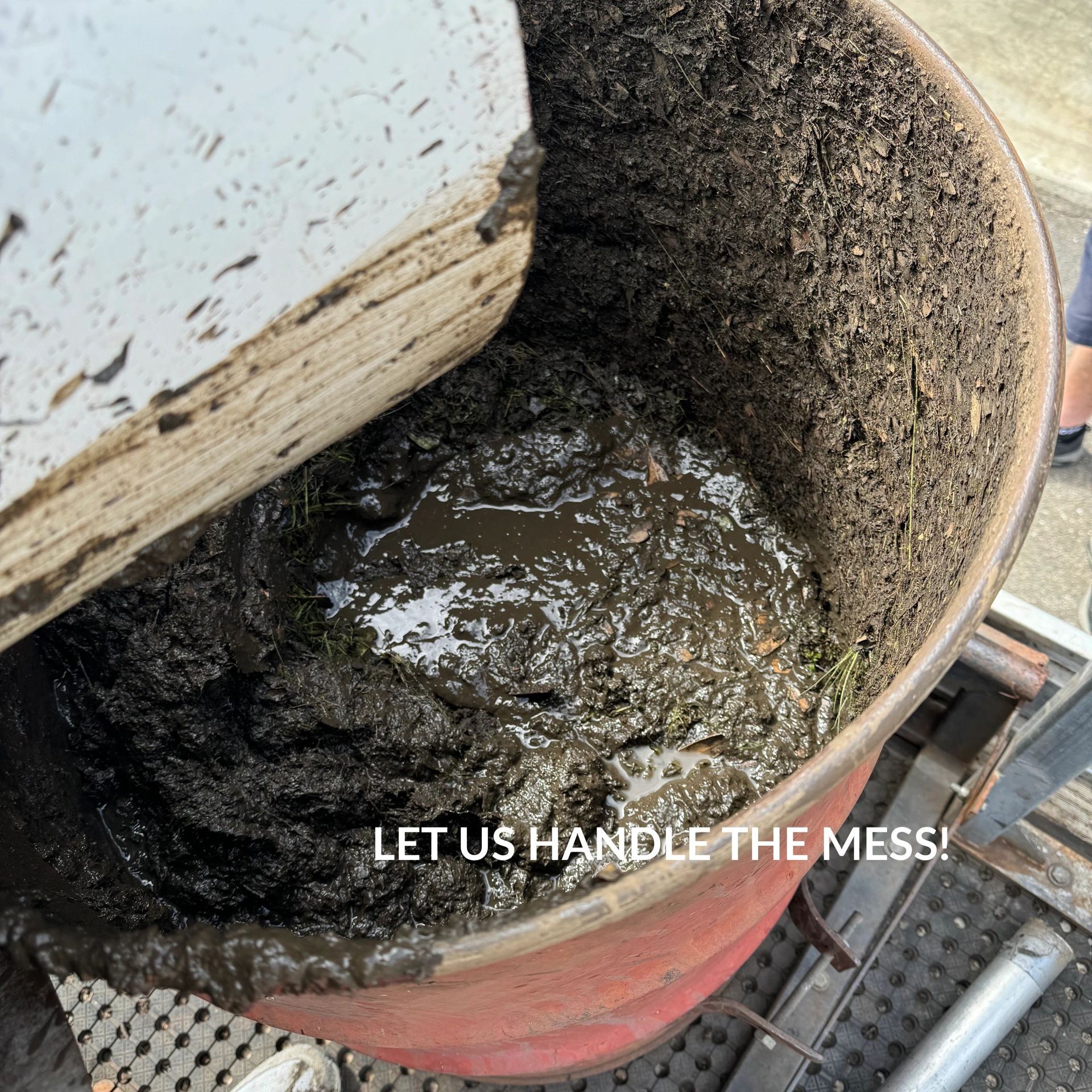 Close-up of a large barrel filled with thick, muddy sludge collected from gutter cleaning, with the