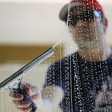 Peak Clean technician using a squeegee to clean a window, delivering streak-free, crystal-clear resu