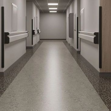 Empty hospital corridor with modern lighting and handrails.