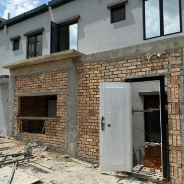 Partially constructed brick and concrete structure with an open door and window frames.