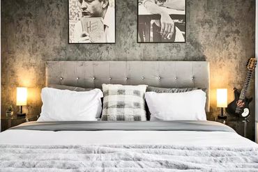 Modern bedroom with tufted headboard, soft bedding, and artistic black-and-white photos.