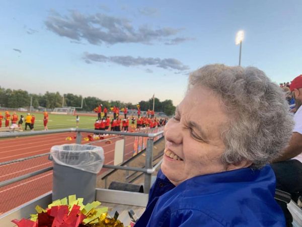 Smiling elderly woman enjoying a sports event at a stadium.