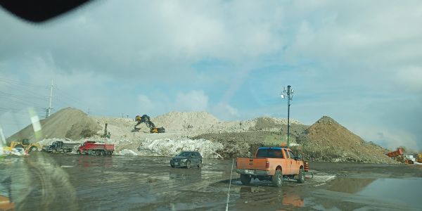 Construction site with excavators and vehicles on muddy ground.
