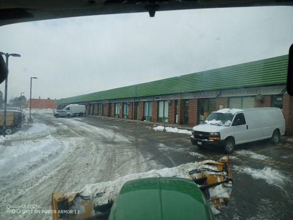 Snowy parking lot with vans and a green-roofed building.