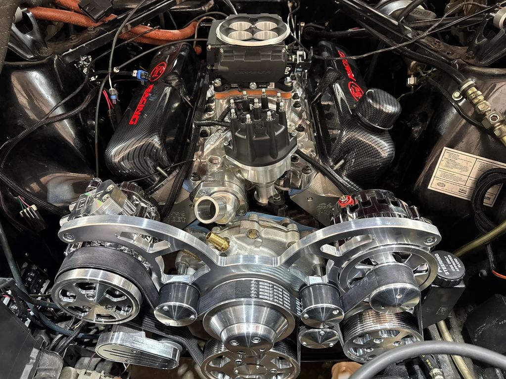 Close-up of a high-performance car engine with polished components and carbon fiber valve covers.