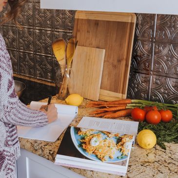 a woman cooking in the kitchen reading a recipe book