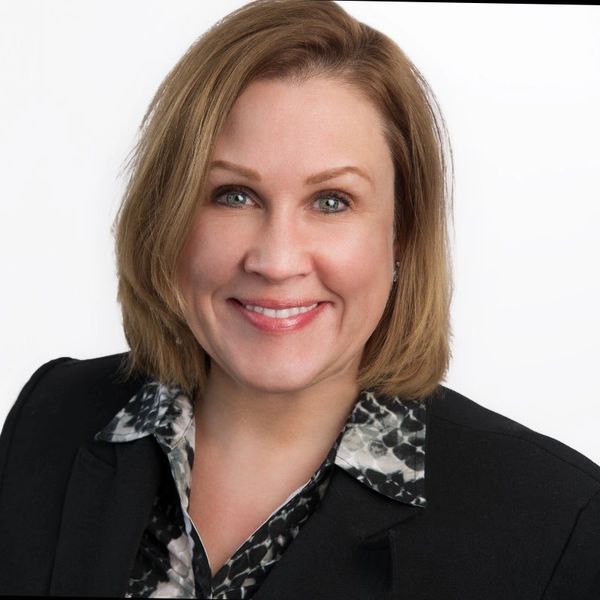 Smiling woman in business attire against white background.